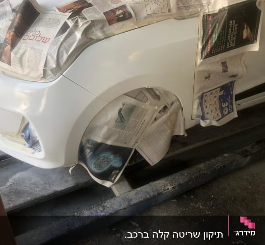 רכב בתהליך צביעה עם עיתונים להגנה על חלקים אחרים.